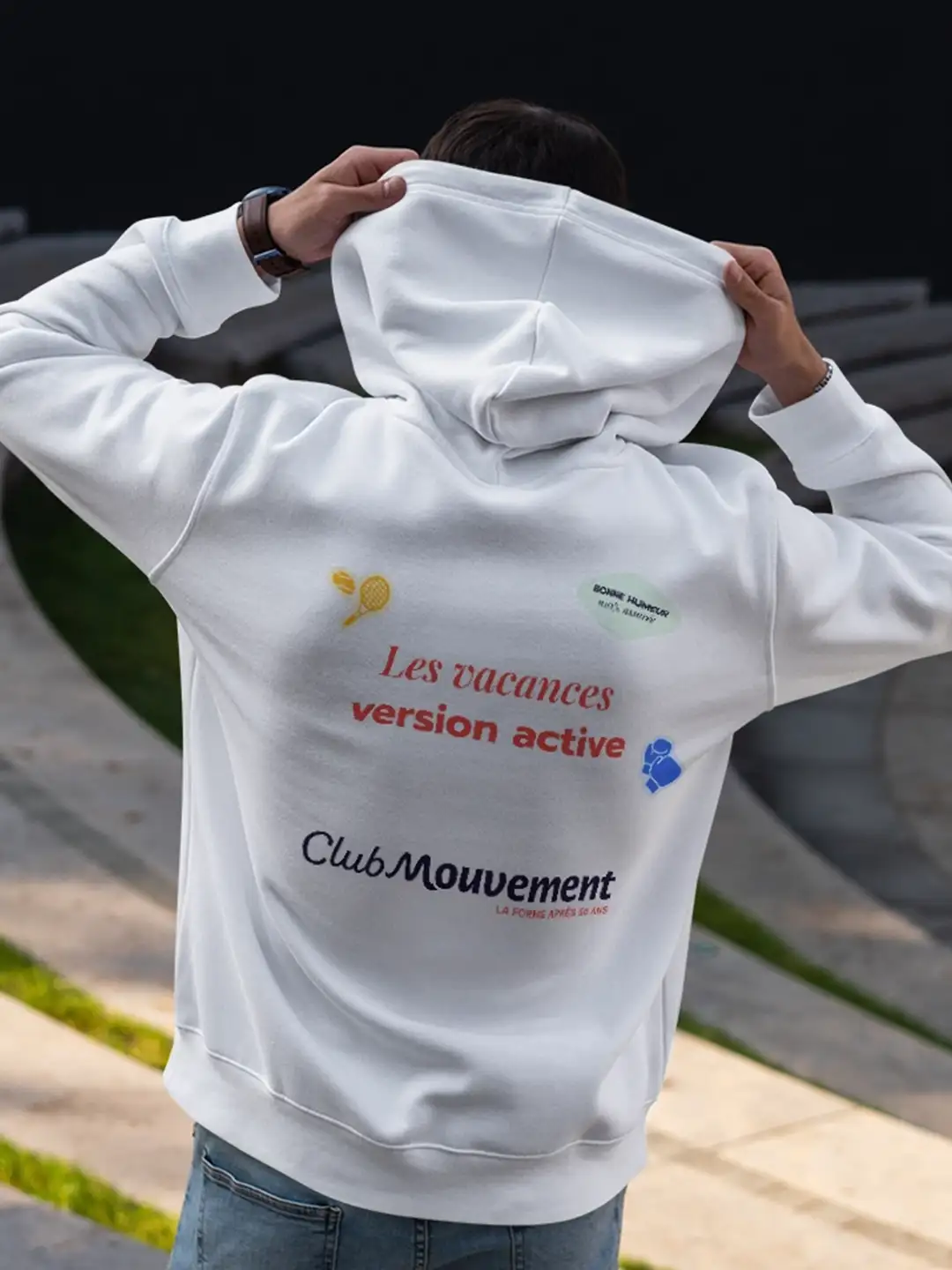 identite-visuelle-club-mouvement-sweat-mockup Logo de marque de séjours actifs pour seniors avec en fond une femme en tenue de sport faisant son footing en extérieur